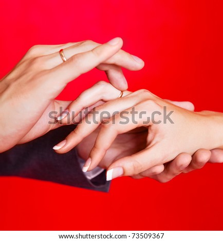 hands of a bride and a groom, man putting a wedding ring on the finger of his bride