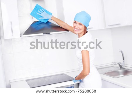 beautiful young housewife cleaning the kitchen hood at home
