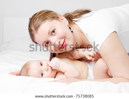 young  mother and her six months old baby on the bed at home (focus on the baby)