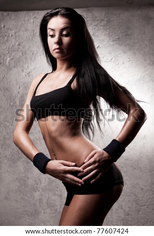 beautiful young sporty muscular woman with long hair in the gym against the old wall