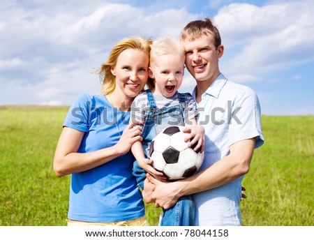 happy young family playing football outdoor on a summer day