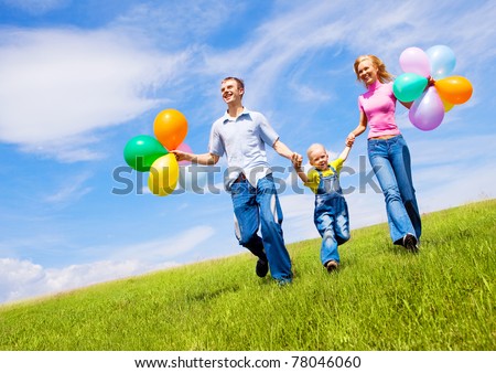 happy family walking with balloons outdoor on a warm summer day