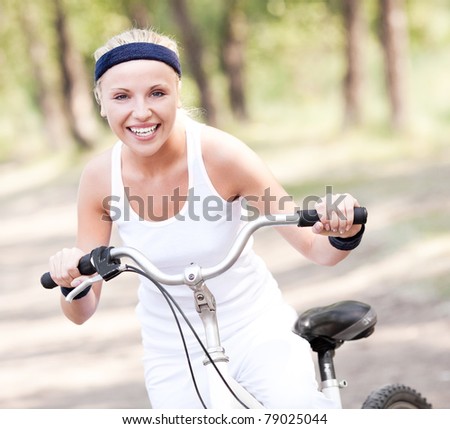 beautiful young blond woman  riding a bicycle on a warm summer day