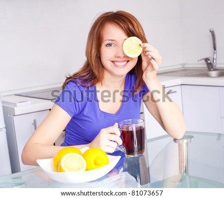 pretty young woman drinking black tea with lemons in the kitchen at home