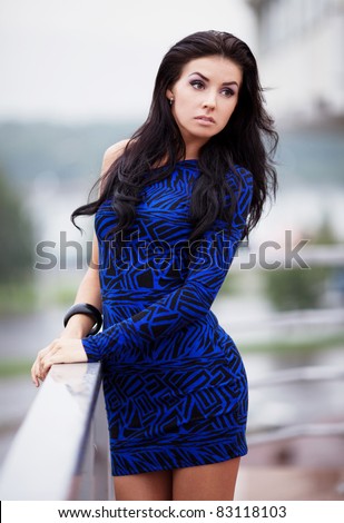 very beautiful young brunette woman wearing a blue mini dress in the street