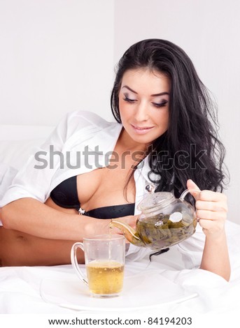 sexy brunette woman drinking green tea on the bed at home