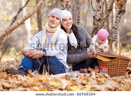 happy young family with their daughter spending time outdoor in the autumn park (focus on the man)