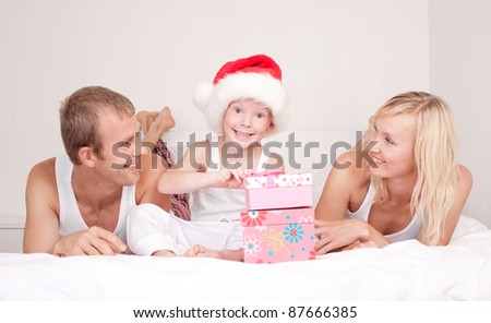 happy family celebrating Christmas and opening presents: mother ,father and their son on the bed at home