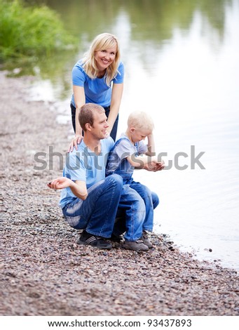 happy family  having a walk near the lake and throwing stones into the water outdoor on a summer day