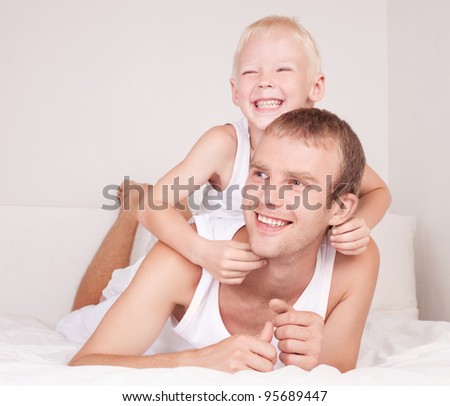 happy laughing father and son in bed at home