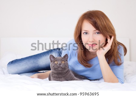 pretty happy young woman with her cat in bed at home