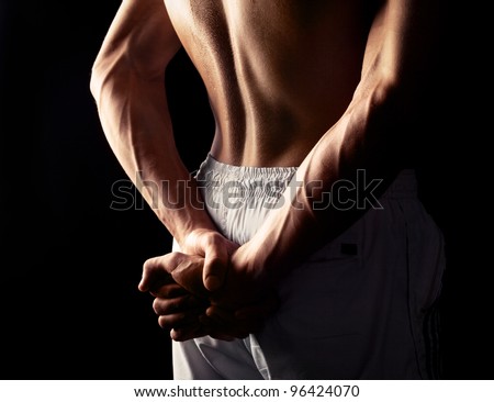 arms and back of a young muscular man, isolated against black studio background