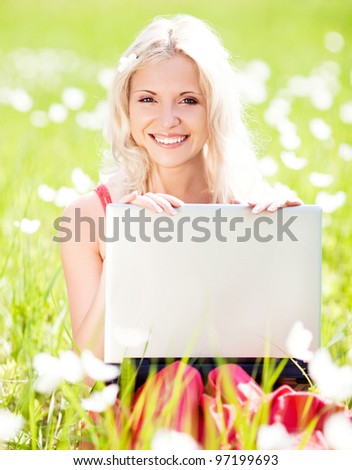 beautiful young blond woman with a laptop  in the park  on a warm summer day