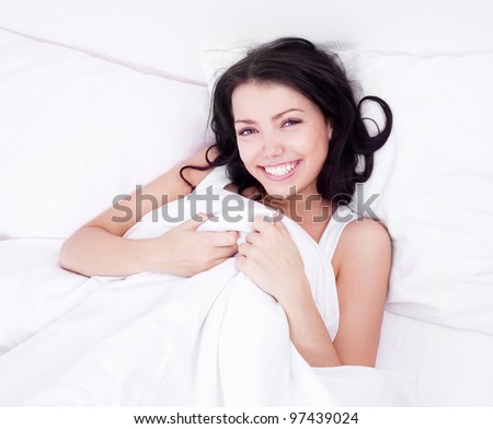 beautiful young brunette woman relaxing in bed at home