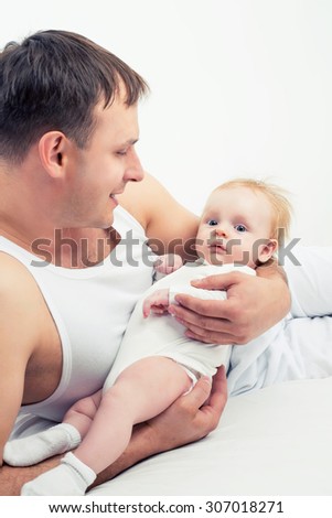 father kissing his two months old baby, in bed at home