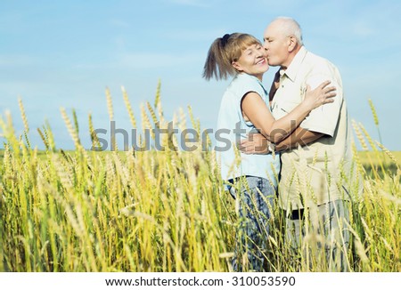 happy couple: sixty eight year old man and sixty five year old woman outdoor at the wheat field