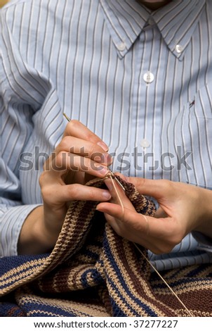 hands of a woman knitting with cotton and metal knitting needle