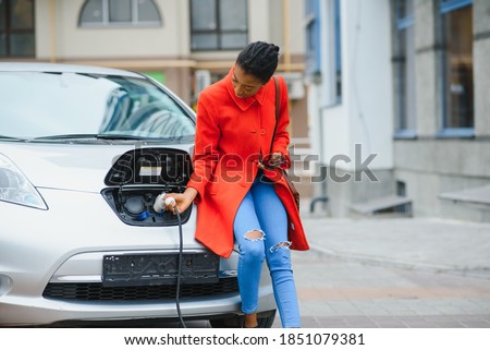 Similar – Image, Stock Photo An elegant woman charging an electric car in urban settings