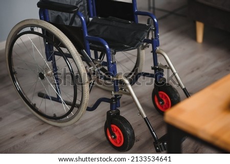 Empty wheelchair in black with large wheels and manual controls on home background. Barrier-free area. Nobody. Apartment room. House. Medical equipment rental. Copy space. Disabled mobility. Banner. Stock foto © 