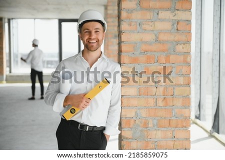 Portrait of an architect builder studying layout plan of the rooms, serious civil engineer working with documents on construction site, building and home renovation, professional foreman at work Stock fotó © 