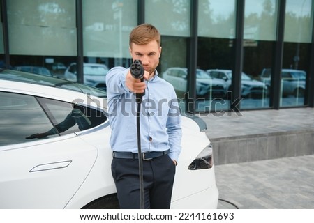 Similar – Foto Bild Mann schließt Elektroauto an Ladestation vor seinem Haus an