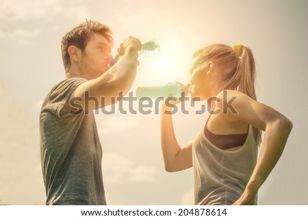 Couple drinking water after workout at sunset