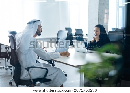 Man and woman with traditional clothes working in a business office of Dubai. Portraits of  successful entrepreneurs businessman and businesswoman in formal emirates outfits. Concept about middle east Stock foto © 