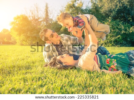 happy and playful parents with kid. Mom holding up his son at the park