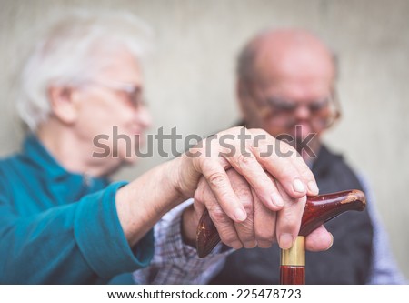 old couple. old man an woman still together holding each other hands over the man cane
