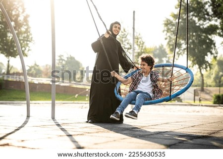 Similar – Image, Stock Photo Father and mother swinging their baby sitting on the green grass in the park. Infant is laughing happy.