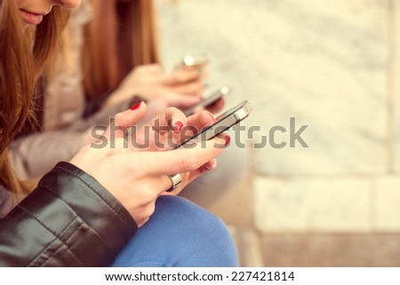 Girls typing on mobile phones - Three friends holding smart phones and chatting