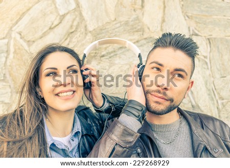 Couple of lovers listening music with one earphone - Friend sharing one earphone