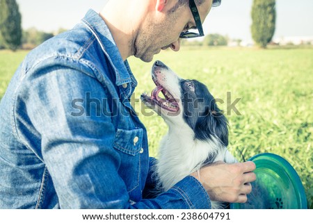 Young man stroking his playful dog - Cool dog and young man having fun with frisbee in a park - Concepts of friendship,pets,togetherness