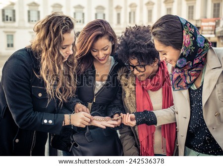 asian girl showing to her mixed race friends a gold bracelet that she just bought. concept about shopping and friendship