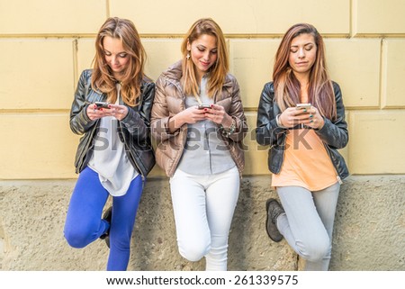Girls typing on mobile phones - Three friends holding mobile phones and chatting - Youth,technology and communication concepts