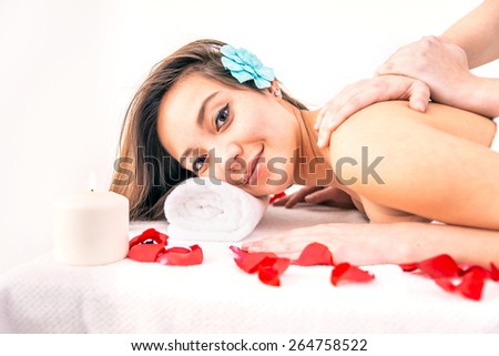 Spa treatment - Beautiful young woman lying and looking at camera while massage therapist massaging her shoulders - Asian girl enjoying massage