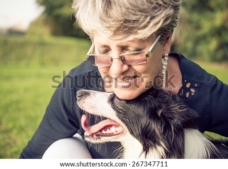 middle age woman hugging her border collie. concept about animals and people