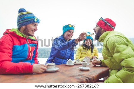 group of friends take a break in a mountain chalet. Eating hot chocolate and cakes