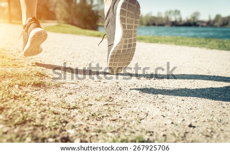 runner on the path. woman training in the park. focus on the ground and shadow. concept about sport and healthy lifestyle