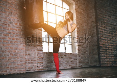 kick at the heavy bag. woman making kickboxing training at the heavy bag