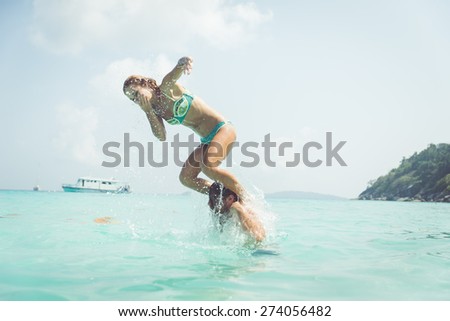 playful couple in the water. woman jumping in the water from the man shoulders. concept about vacations, fun and people
