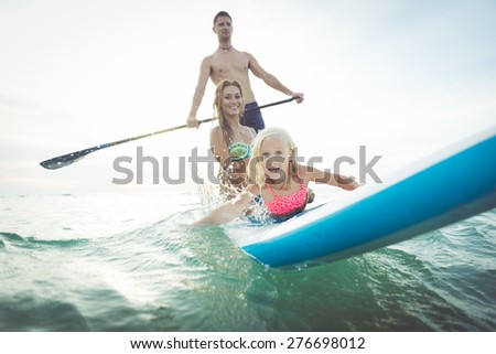 family making paddle surf in the ocean. concept about sport, healthy lifestyle and people