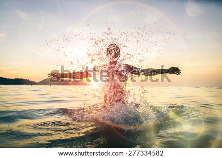 Man splashing water during summer holidays - Young attractive man having fun on a tropical beach at sunset