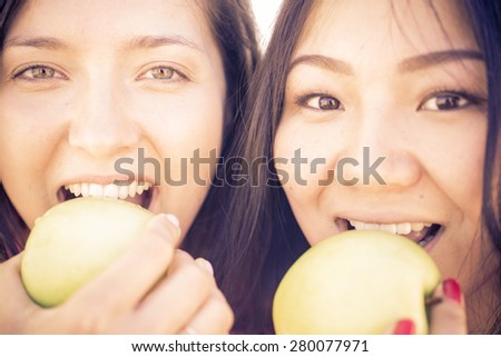 couple of girls biting green apples. concept about food, health care and people
