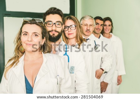 Group of doctors with white coat in a row - Docs of diverse age in a hospital