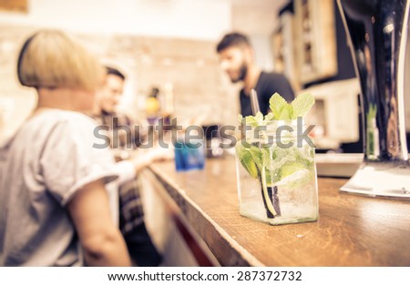 close up on a cocktail in a bar. barman and customers are standing in the back. concept about bar, profession and people.