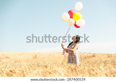 beautiful asian woman in a wheat field with air balloons. concept about airiness and carefree