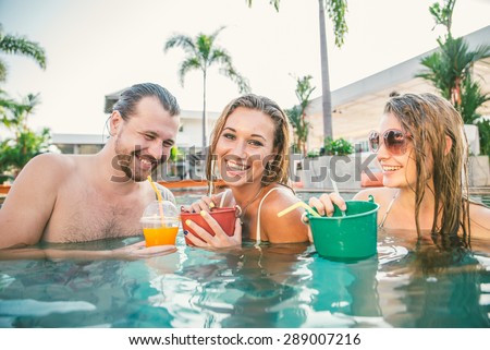 Friends having party and drinking buckets at a swimming pool party - Tourists on vacation in a beautiful tropical resort during summertime