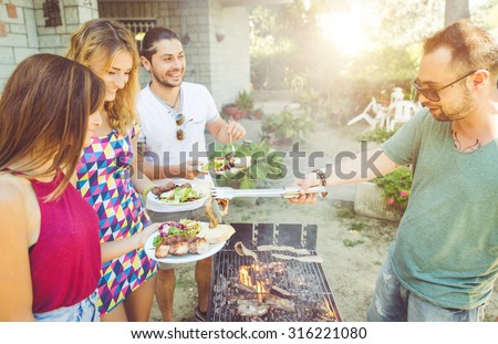 group of friends making barbecue in the garden backyard. friends sharing food and happy moments