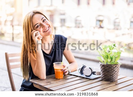Young pretty woman talking at phone with friend while sitting in a bar outdoors - Businesswoman calling for a meeting - Beautiful girl in a restaurant